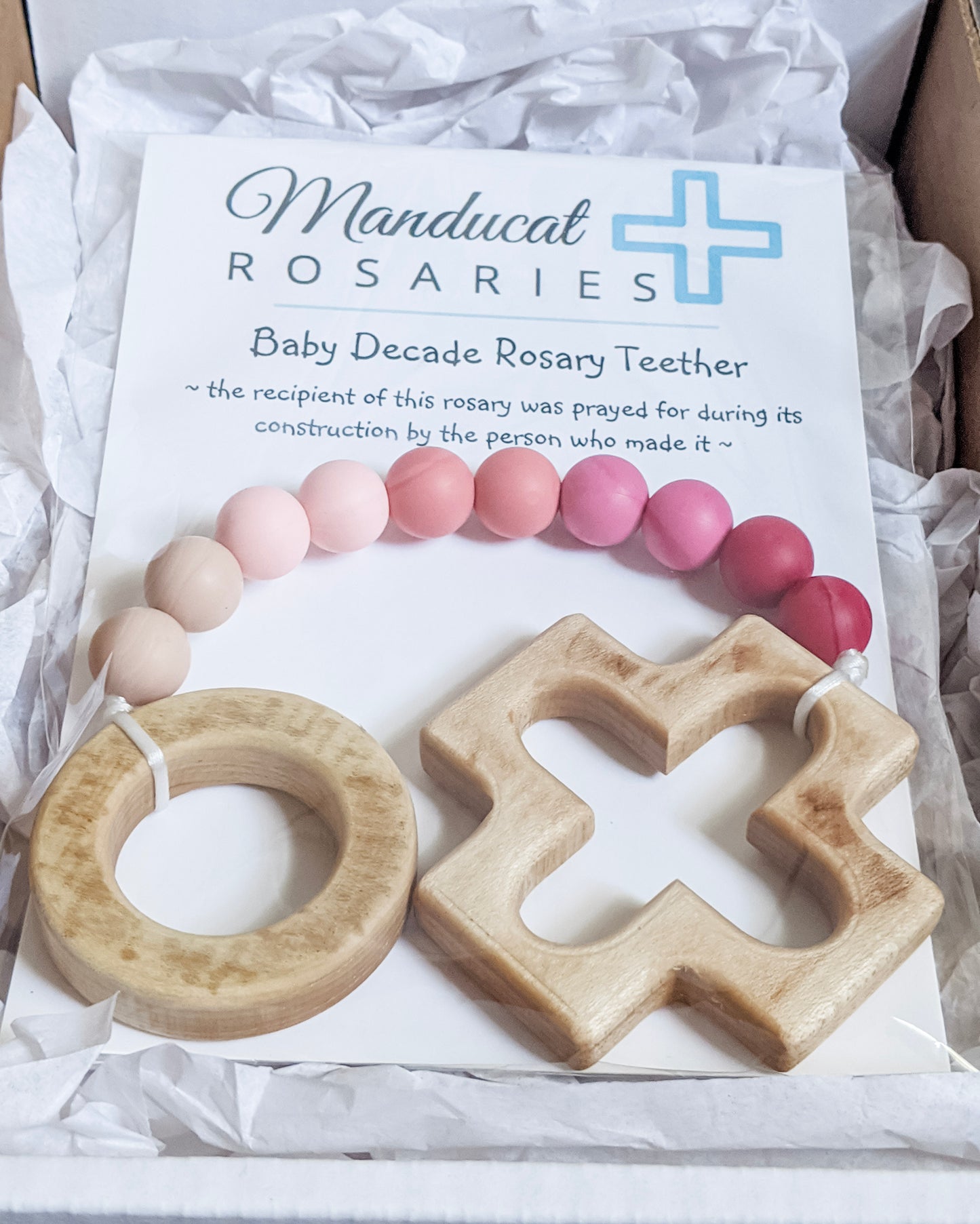 Pink ombre rosary in packaging stating baby was prayed for during item's construction