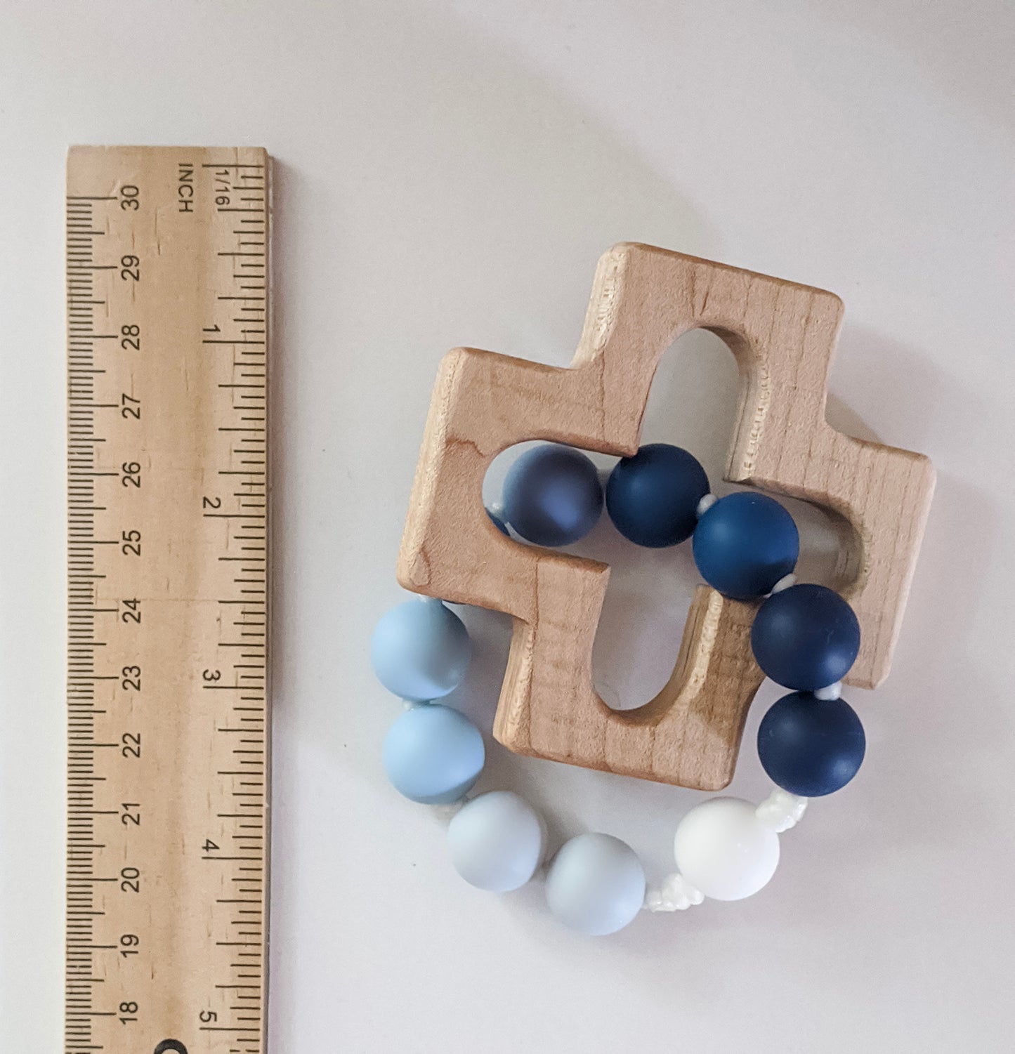 Teething ring with cross wood piece next to ruler