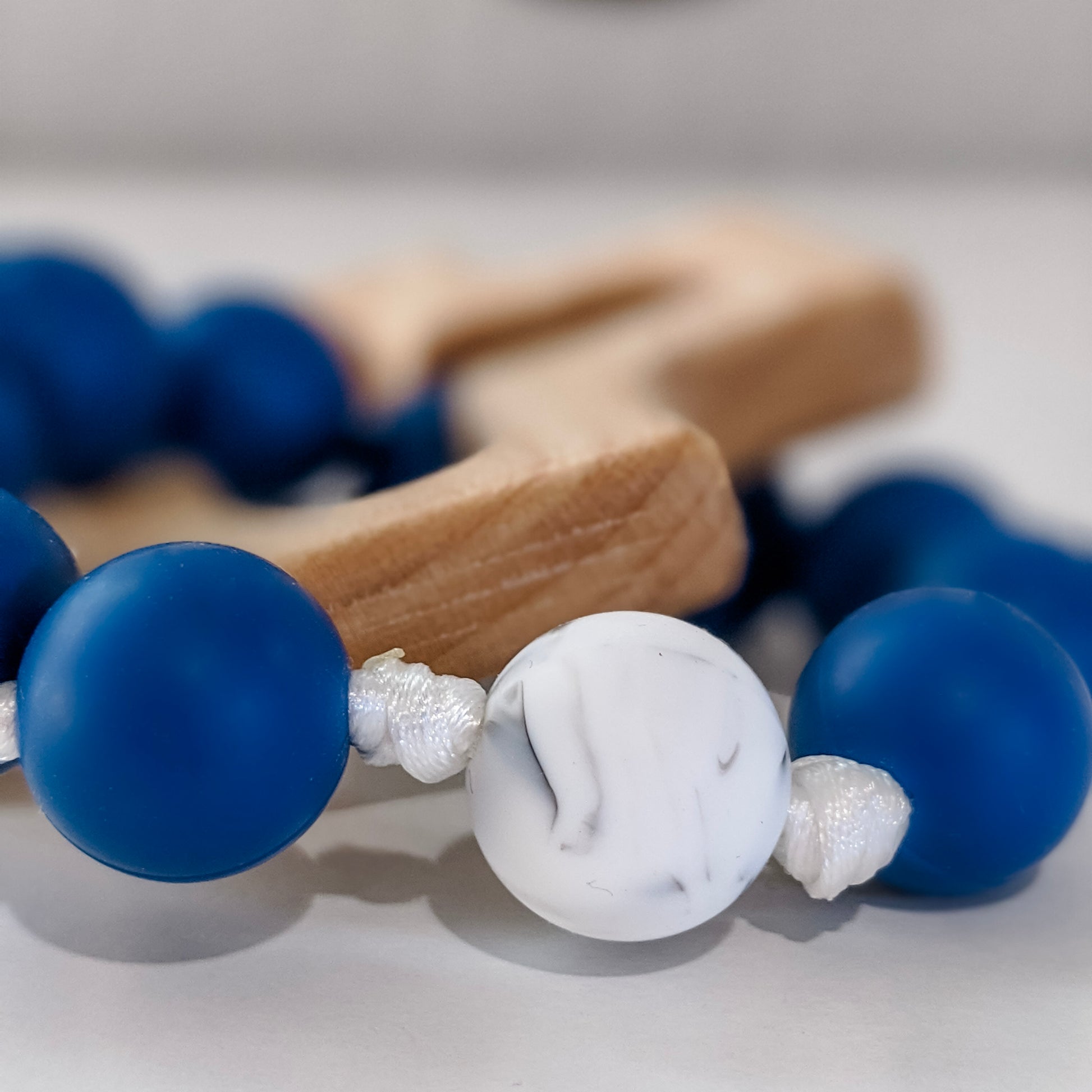 Close up of marble white Our Father bead on baby rosary teething ring