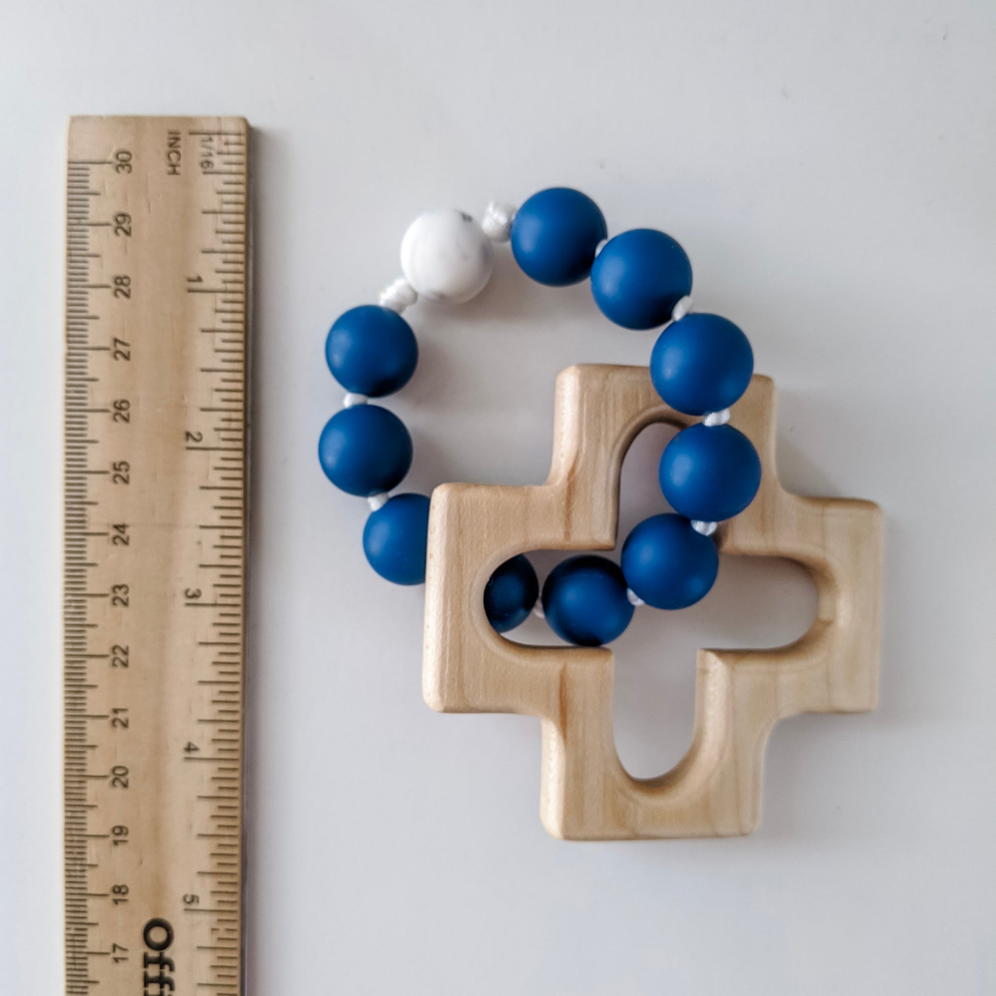 Blue and white marble silicone rosary ring next to ruler