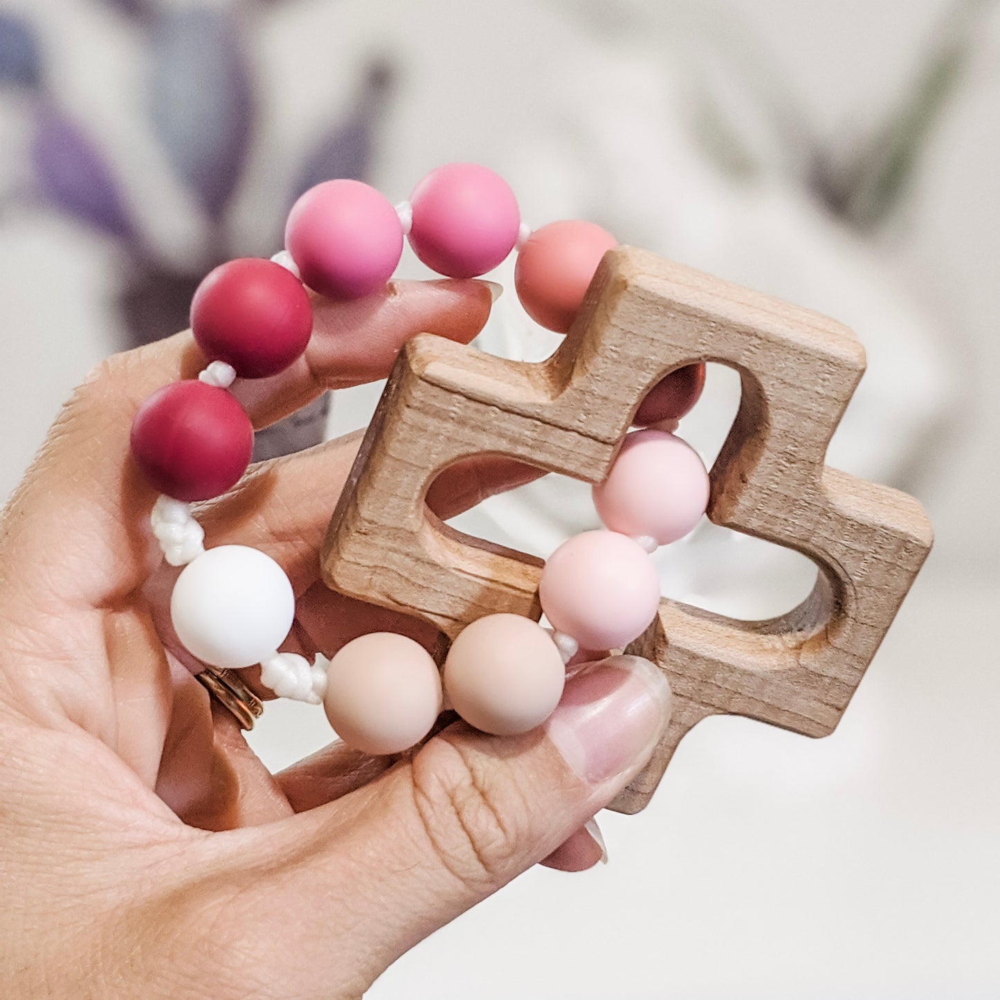 Teething rosary ring in pink ombre held in hand