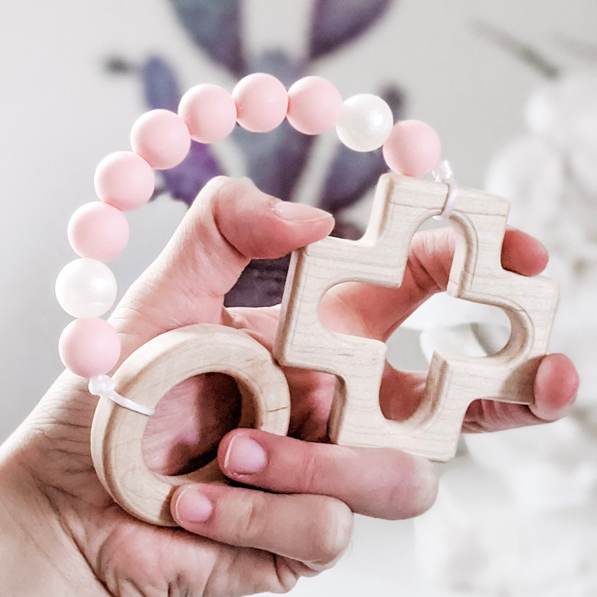 Pink and pearl silicone rosary teething strand in hand