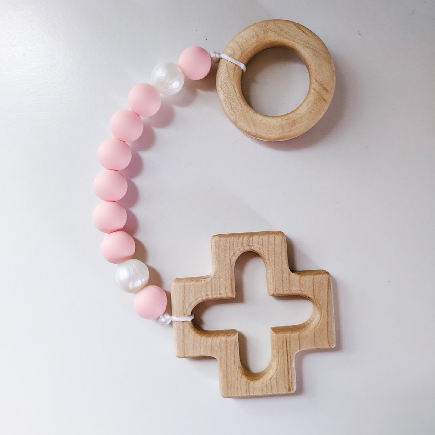 Pink and pearl teething rosary on white background