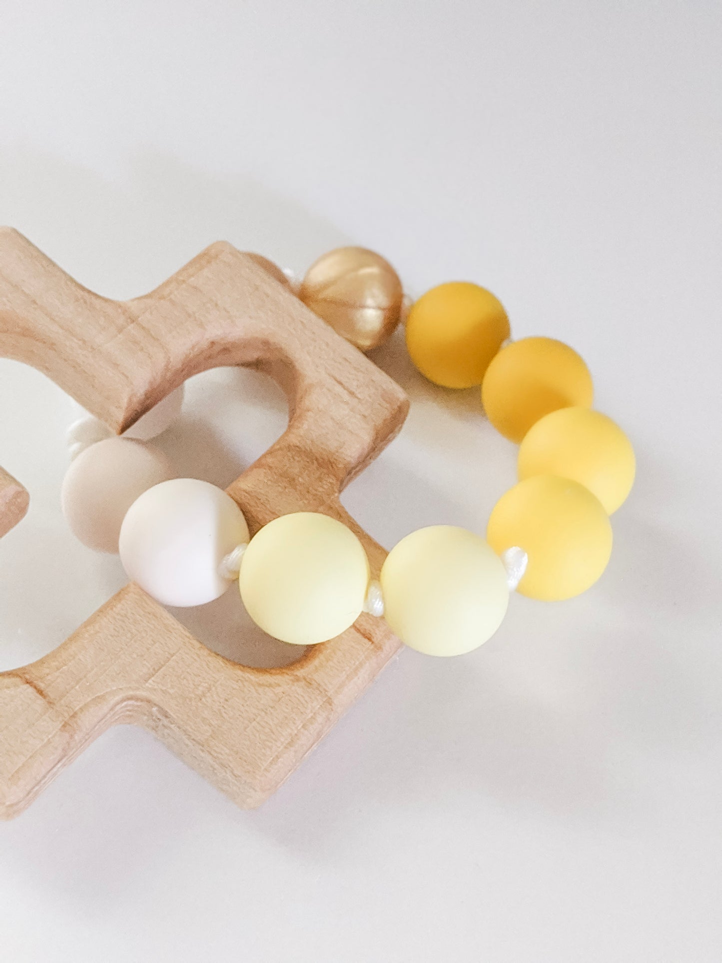 Close up of light yellow side of yellow ombre silicone bead teething ring