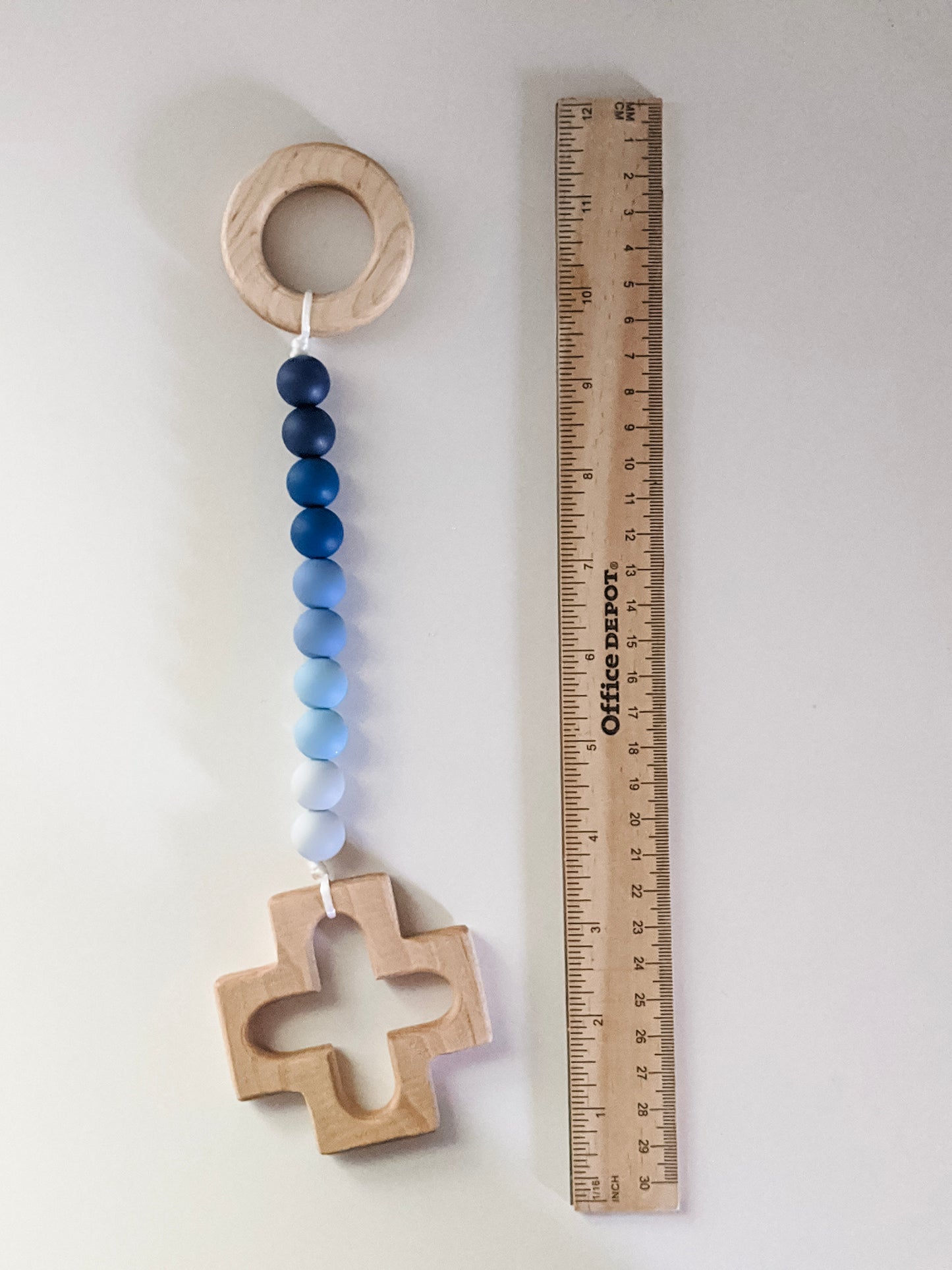 Rosary teething strand in ombre blue next to ruler