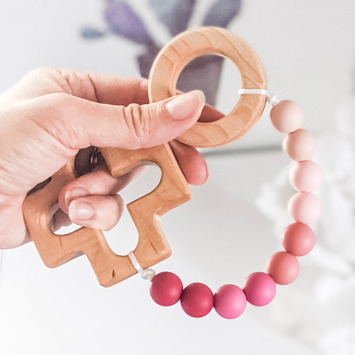 Hand holding pink ombre decade rosary teething strand.