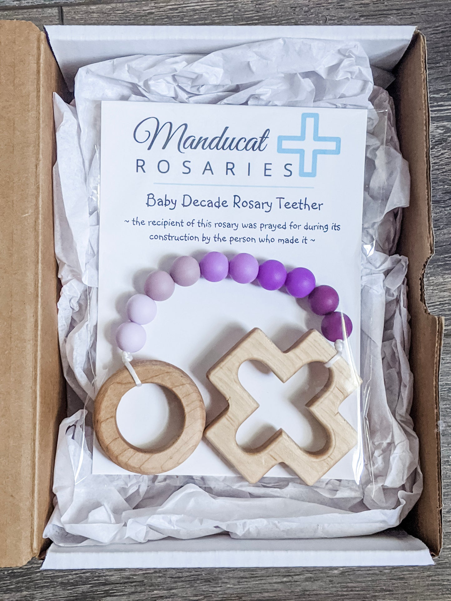 Purple ombre teething rosary in packaging stating the baby was prayed for during the item's construction